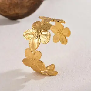 Gold flower cuff bracelet with textured petals and wide band, made using hydraulic press jewelry process