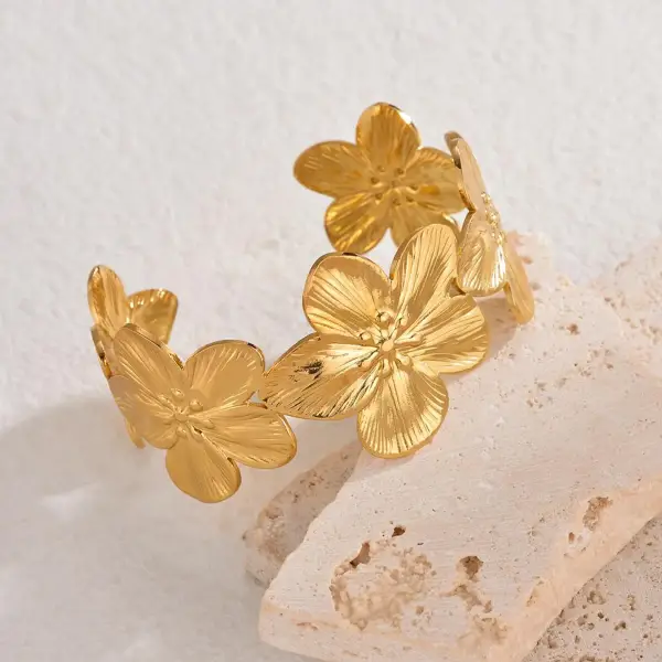 Gold flower cuff bracelet with textured petals and wide band, made using hydraulic press jewelry process