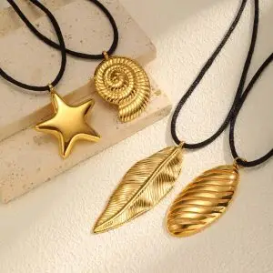 Gold nature pendant necklace set with star, shell, and leaf charms on black rope cords