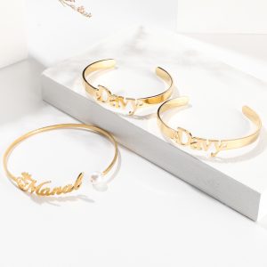 Gold stainless steel custom name bracelets with Davy and Manal lettering, including pearl accent bangle